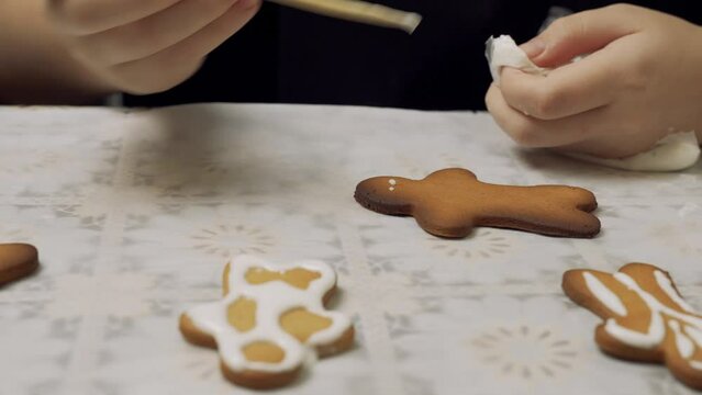 A girl paints gingerbread cookies with sugar cream. Prepares gingerbread cookies. Close-up.