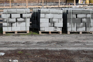 Stacks of concrete blocks on wooden pallets at a construction site. Building materials organized outdoors, industrial background, daylight