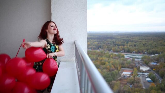 young girl stands on the balcony with balloons and throwing one of them