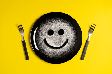 Smiling face, concept made with plate and flour, yellow background, star shaped eyes, black plate,...