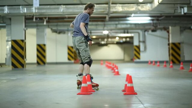 Man on roller skates taking run and breaking slide near cones on parking.