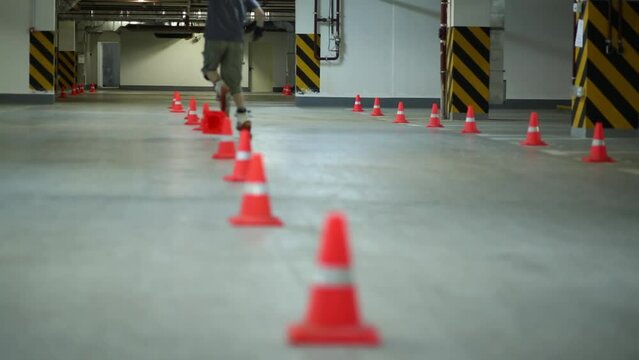 Guy circling line of cones and overthrowing one on one leg on roller skates