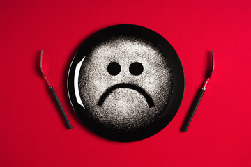 Sad face, concept made with plate and flour, red background, star shaped eyes, black plate, happy mood, facial expressions, forks in the shape of arms with different positions