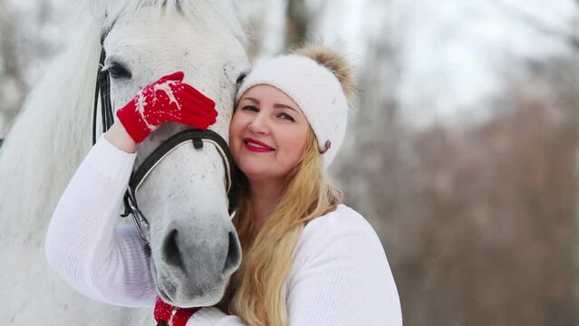 Beautiful girl hugging and petting a horse in the forest