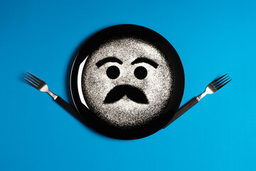 Happy face, face with mustache, concept made with plate and flour, blue background, black plate, facial expressions, forks in the shape of arms with different positions