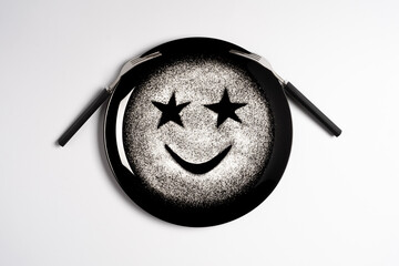 Smiling face, concept made with plate and flour, white background, star shaped eyes, black plate, happy mood, facial expressions, forks in the shape of arms with different positions