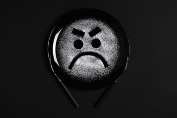 Displeased face, frowning eyebrows, concept made with plate and flour, black background, black plate, facial expressions, forks in the shape of arms with different positions