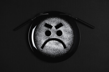 Displeased face, frowning eyebrows, concept made with plate and flour, black background, black plate, facial expressions, forks in the shape of arms with different positions
