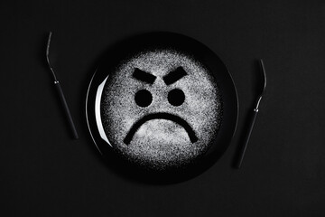 Displeased face, frowning eyebrows, concept made with plate and flour, black background, black plate, facial expressions, forks in the shape of arms with different positions