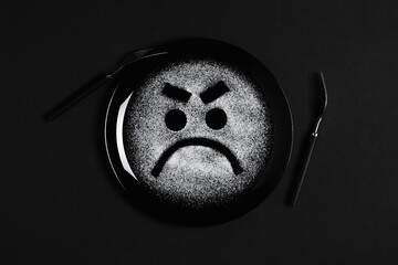 Displeased face, frowning eyebrows, concept made with plate and flour, black background, black plate, facial expressions, forks in the shape of arms with different positions