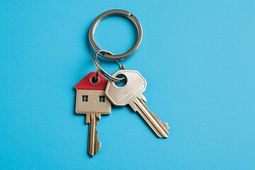A house key in the shape of a house on a blue background, depicting the concept of house ownership, buying a house, or real estate investment
