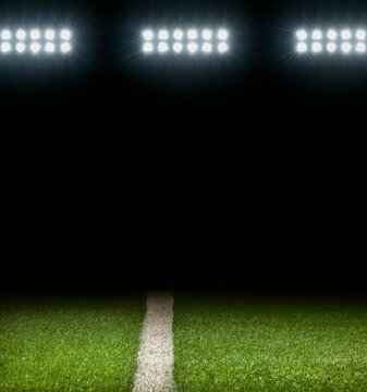 Grass athletic field with white stripe and dark background below stadium lights