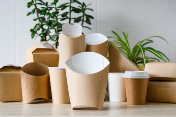 New paper packaging for French fries against the background of disposable eco-friendly tableware. Place for logo