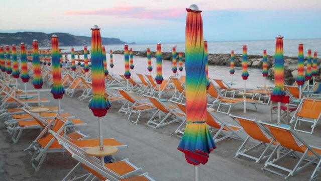 Many colorful deck chairs and folded umbrellas on the beach