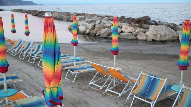 Sunbeds and folded umbrellas on the beach in the evening in Loano, Italy