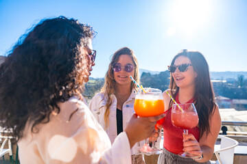 Friends enjoying summer toasting with cocktails on a rooftop