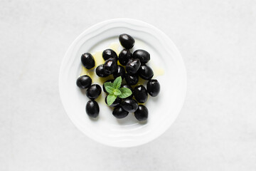 Black olives on a white plate, pitted Black olives on a ceramic plate