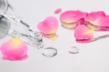 Liquid serum and pipette with rose petals, beauty concept