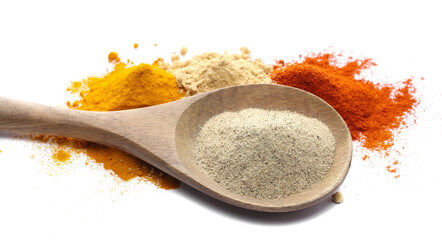 White pepper powder in wooden spoon with cayenne pepper, ginger and turmeric ground isolated on white