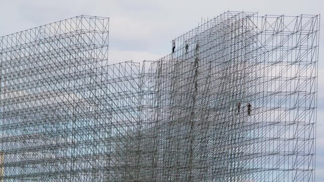 People work on falsework and pass by chain materials at construction site