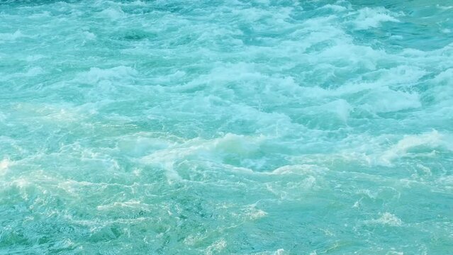 Rapidly seething stream of water. Big powerful river waves. White foam and water ripple. Foaming and splashing in the ocean. Strong flow of a mountain river. Blue clear water