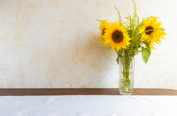 A bouquet of beautiful sunflowers in a glass vase on the table. Floral design concept.
