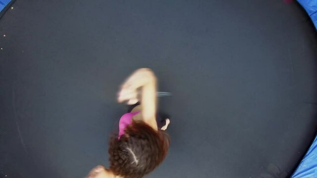 Woman in sports suit jumps on round trampoline. Aerial view