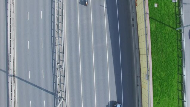 Cars and many bikers ride by road at sunny day. Aerial view