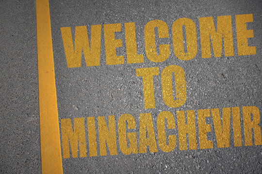 asphalt road with text welcome to Mingachevir near yellow line.