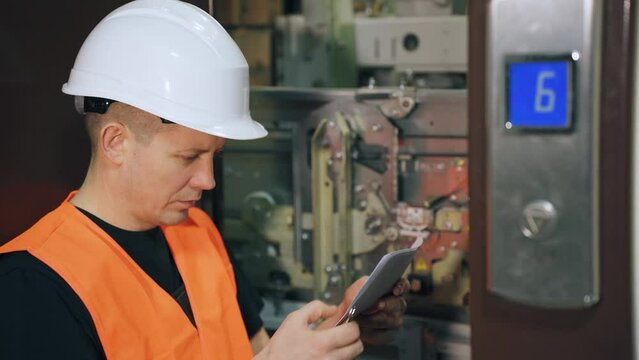 Installation of an elevator cabin in a residential complex. A male utility worker adjusts the lift mechanism. Elevator stop in the elevator shaft.