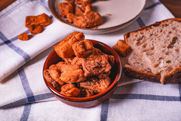 Heap of domestic salty fried pork greaves. Fatty junk food. Pork greaves on the kitchen board.