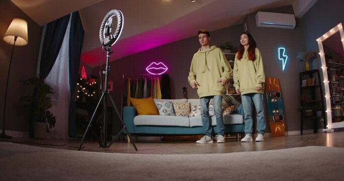 TikTokers are filming video for social networks dancing popular dance at home in front of ring lamp on tripod. TikTokers are constantly looking for ways to reach audience and expand online presence.