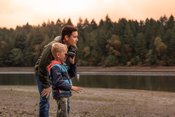 Father and son outdoors family adventure discovering nature together looking at wildlife with...