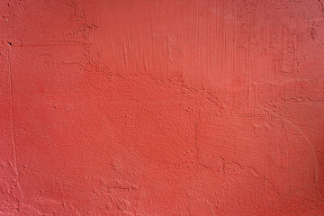 A bold red textured plaster wall, full frame shot perfect for vibrant backdrops and graphic designs