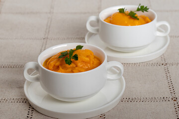 Pumpkin soup. Home cooking, preparing meal at home. Two portions of pumpkins soup in identical tureens