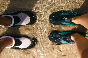 High angle view of two people wearing water shoes in shallow seawater