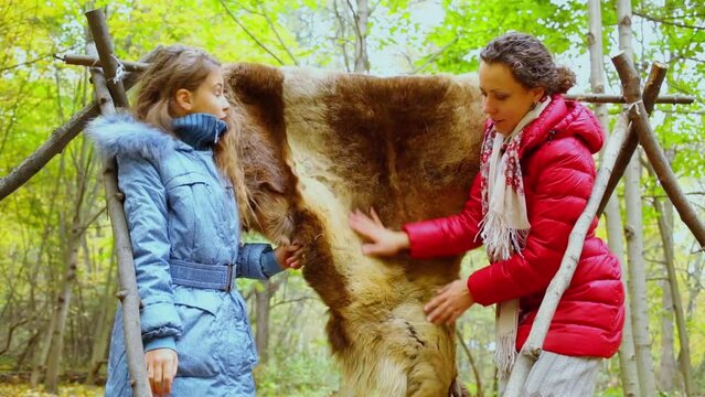 Girl stands near mother which flatters fell at autumn day in forest