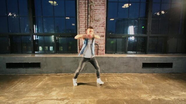Young man moves in break-dance style near large windows