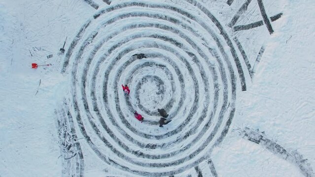 People skate by ice spirals near name Ann on snow at winter day. Aerial view