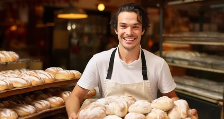 Papier Peint photo Lavable Boulangerie Portrait of a smiling young male baker holding fresh bread in a bakery