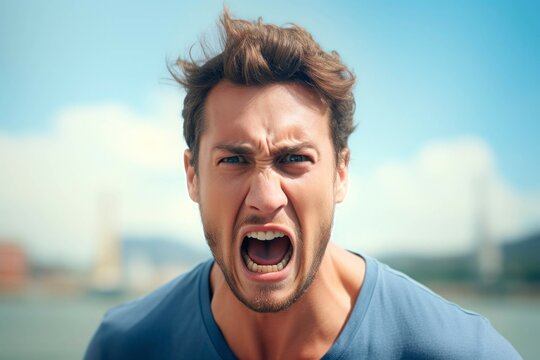 Portrait of angry young man screaming outdoors. Shouting man.