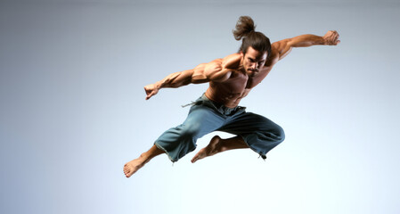 Handsome muscular man jumping, full length portrait on grey background