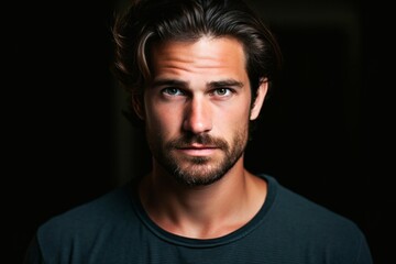 Portrait of a handsome young man looking at camera in dark room