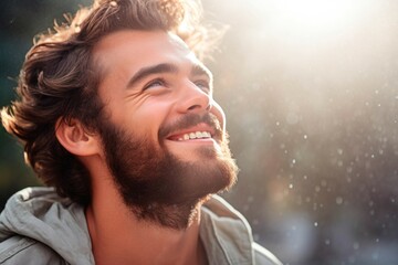 Close up portrait of a handsome young man smiling and looking away outdoors - obrazy, fototapety, plakaty