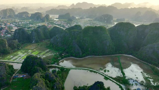 Drone view of Tam Coc valley in Vietnam at sunset, Ngo Dong River at Limestone Mountains Valley in Ninh Binh Vietnam, scenic sunset in Southeast Asia, travel in Asia