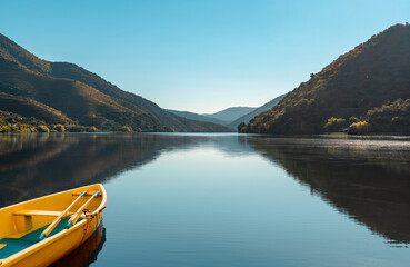 Landscape of a river valley with a yellow boat reflected in the serene waters. Nature travel concept