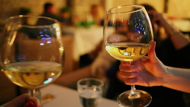 People clinks glasses with white vine at restaurant