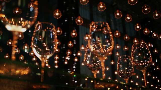 vine glasses stand on glass shelve and many lamps hang from ceiling
