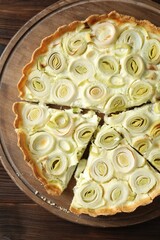 Board with tasty leek pie on wooden table, top view
