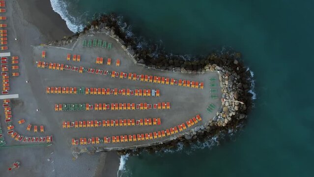 Lot of deckchairs are on beach among stones near sea at summer